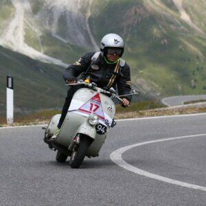 Motorradfahrer mit Schutzkleidung fährt eine Kurve auf einer Bergstraße entlang.