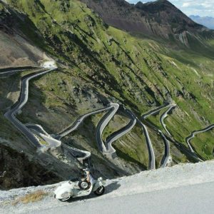 Aus Drohen-Perspektive steht Vespa Faro Basso am Straßenrand - im Hintergrund einige der Serpentinen der Stilfersjoch-Passtraße.