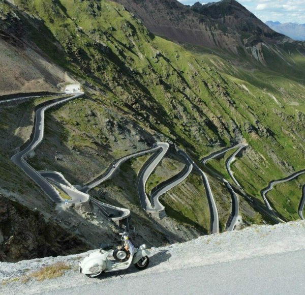 Aus Drohen-Perspektive steht Vespa Faro Basso am Straßenrand - im Hintergrund einige der Serpentinen der Stilfersjoch-Passtraße.