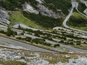 Kurvenreiche Gebirgsstraße mit Serpentinen und umgebender grüner Landschaft.