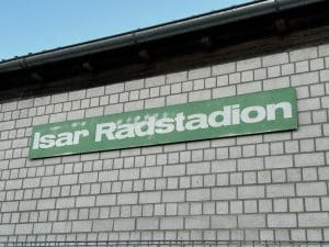 Graues Ziegelgebäude mit grünem Schild, auf dem „Saar Radstadion“ steht.
