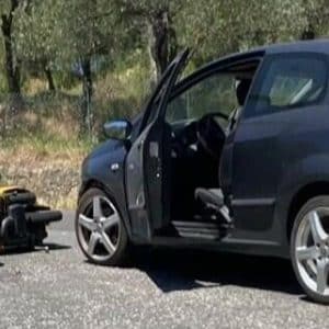 Schwarzes Auto mit offener Tür steht auf einer Landstraße, ein Rollstuhl befindet sich davor auf dem Boden.