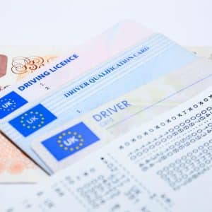 Mehrere europäische Führerscheine und Dokumente liegen gestapelt auf einem weißen Hintergrund.