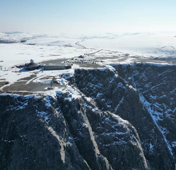 Nordkapp Globus aus der Vogelperspektive - Felsen im Vordergrund und im Hintergrund das Besucherzentrum umgeben von Schnee