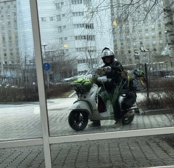 Beladene Vespa GTS mit Olaf H. Just warm angezogen im Spiegel der Fensterfront am Hotel in Umea.