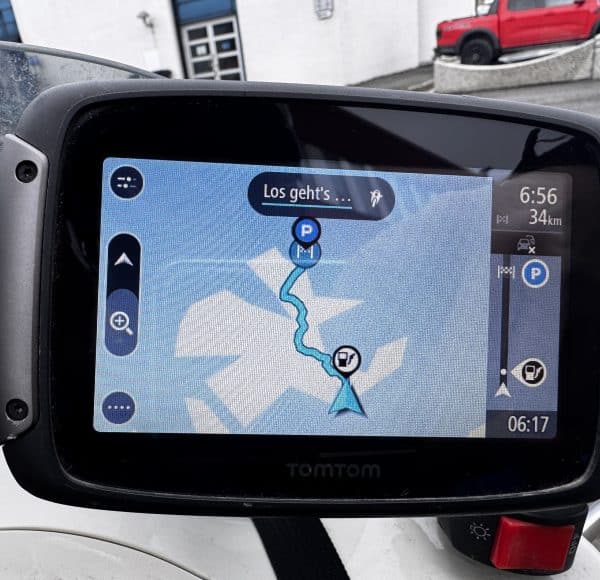 Navigationsgerät zeigt Route auf digitaler Karte, mit aktuellen Richtungsangaben und verbleibender Entfernung, montiert in einem Fahrzeug.