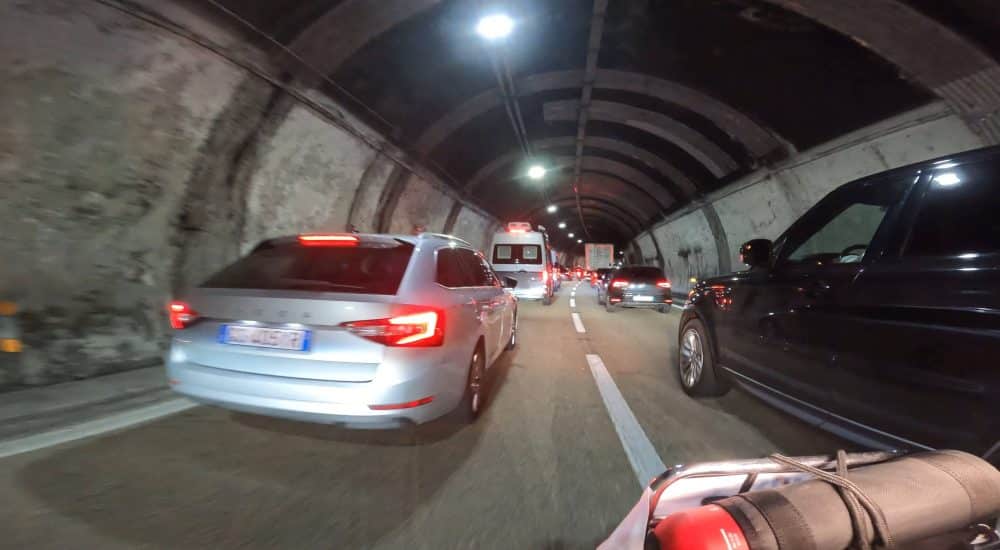 Stau in einem beleuchteten Straßentunnel mit mehreren Autos in beiden Fahrtrichtungen bei Nacht.