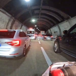 Stau in einem beleuchteten Straßentunnel mit mehreren Autos in beiden Fahrtrichtungen bei Nacht.