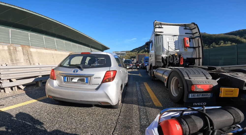 Stau auf der Autobahn mit Autos und Lastwagen bei sonnigem Wetter.