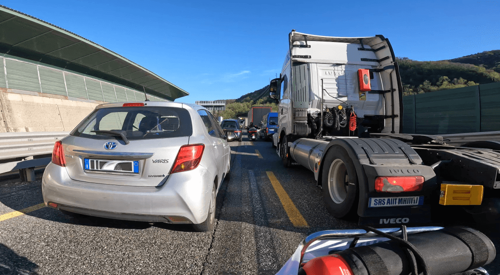 Stau auf der Autobahn mit Autos und Lastwagen bei sonnigem Wetter.