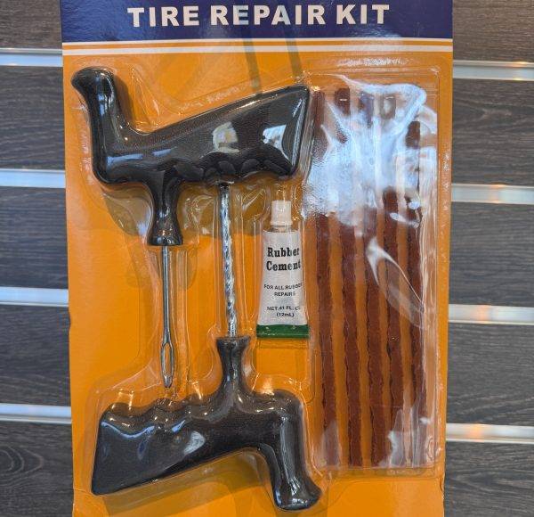 Reifenreparaturset mit Werkzeugen, Dichtstreifen und Kleber in Kunststoffverpackung auf orangefarbenem Hintergrund.