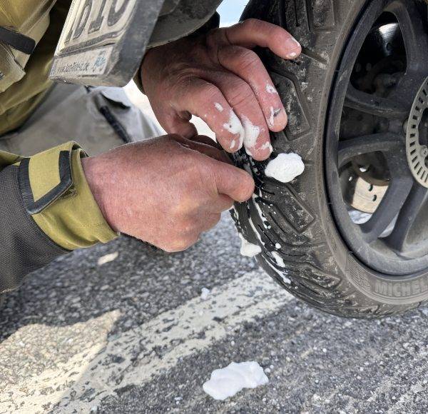 Person repariert einen platten Reifen mit einem Werkzeug auf einer Straße.