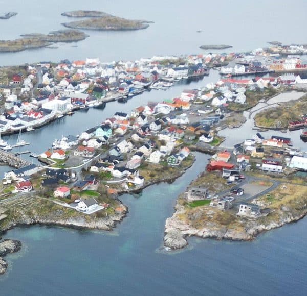 Vogelperspektive auf eine kleine Küstenstadt mit bunten Häusern und Inseln, umgeben von Wasser und Booten.