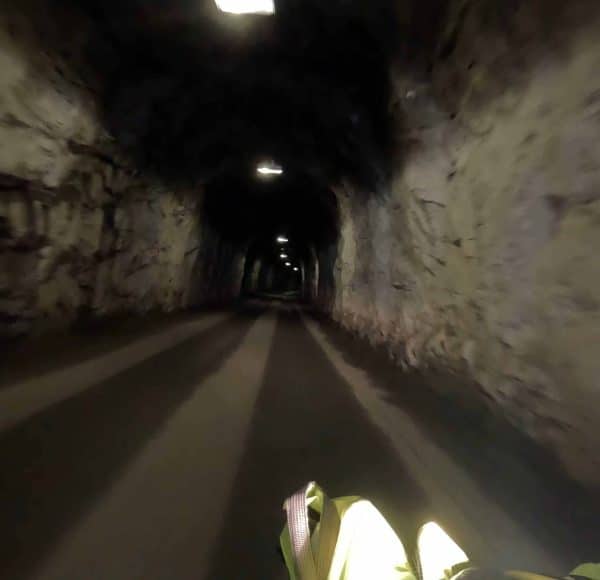 Dunkler, beleuchteter Tunnel aus Stein mit Weg, Tunneldecke und Wänden sichtbar.