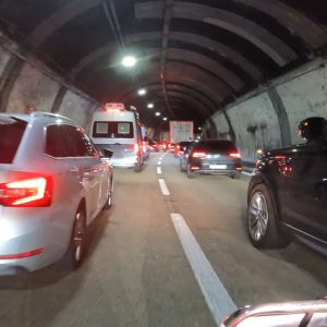 Mehrere Autos stehen im Stau in einem beleuchteten Tunnel, darunter ein Krankenwagen.
