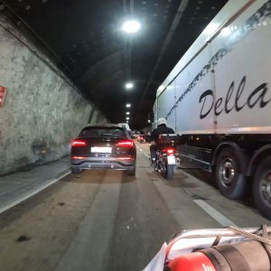 Autos, Motorrad und LKW fahren in einem beleuchteten Straßentunnel mit leichtem Verkehr.
