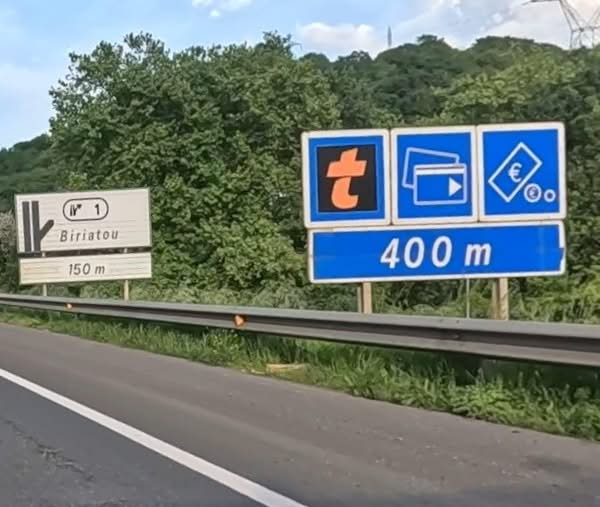 Zwei Verkehrsschilder: eines zeigt Richtung Biriatou in 150 m, das andere informiert über Mautstation in 400 m Entfernung.